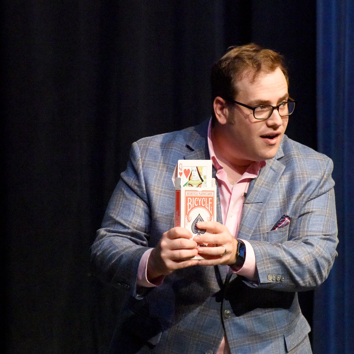 Scott Green holding up an oversized deck of cards on stage