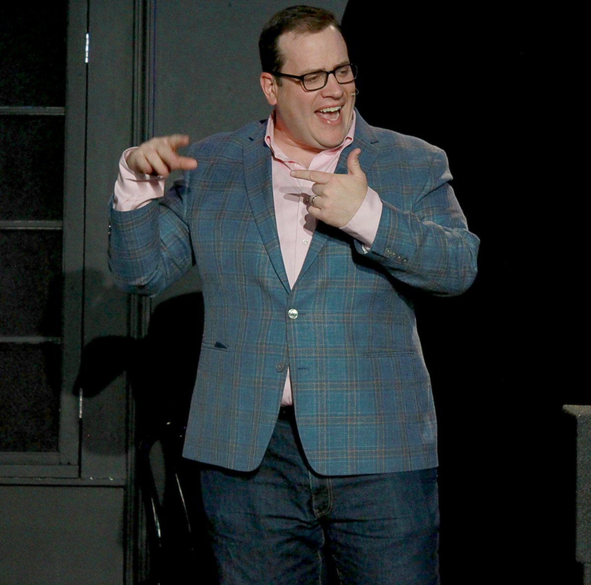 Scott Green mid-joke on stage at iO Theater, grinning and pointing at himself