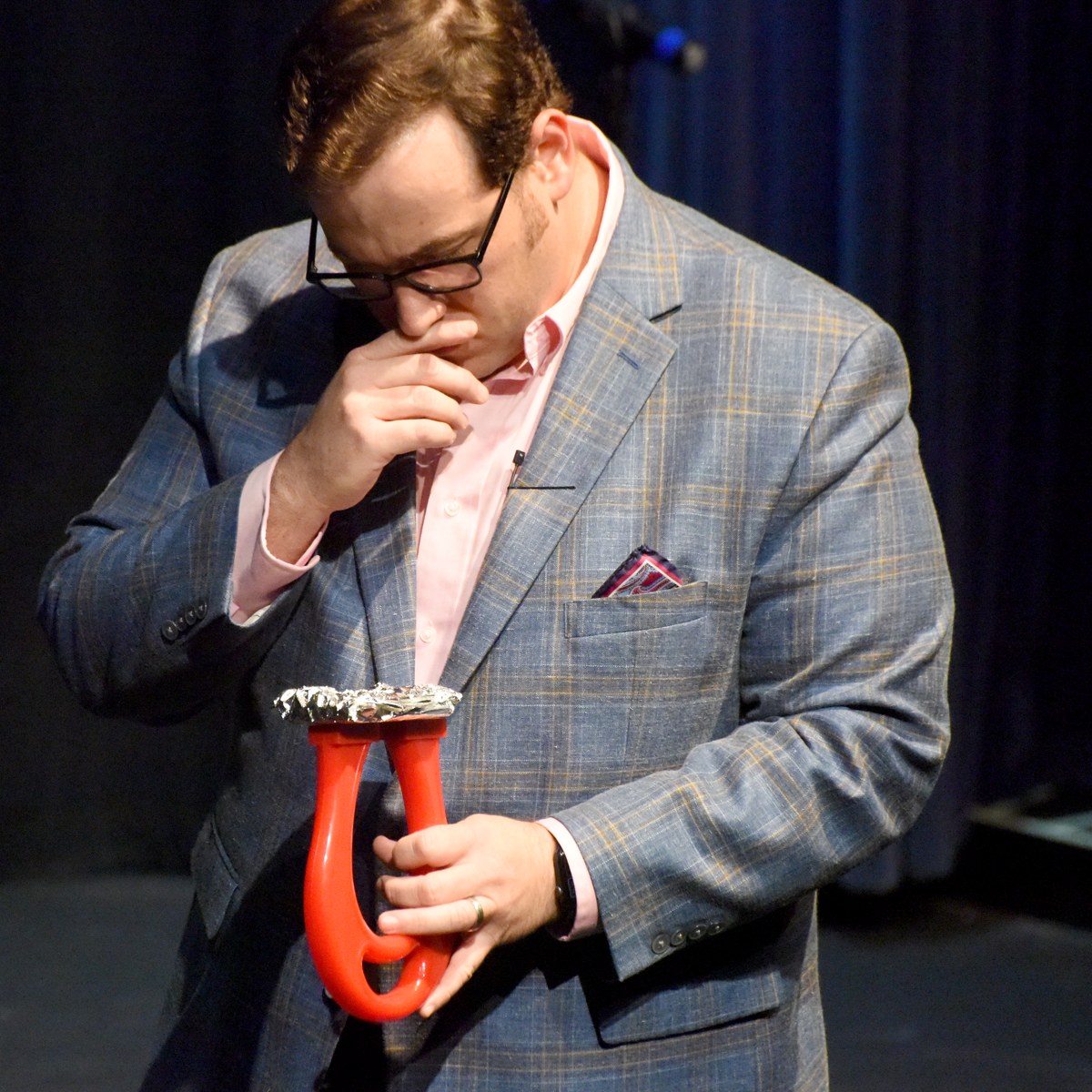 Scott Green looking down at a red prop mid-routine on stage