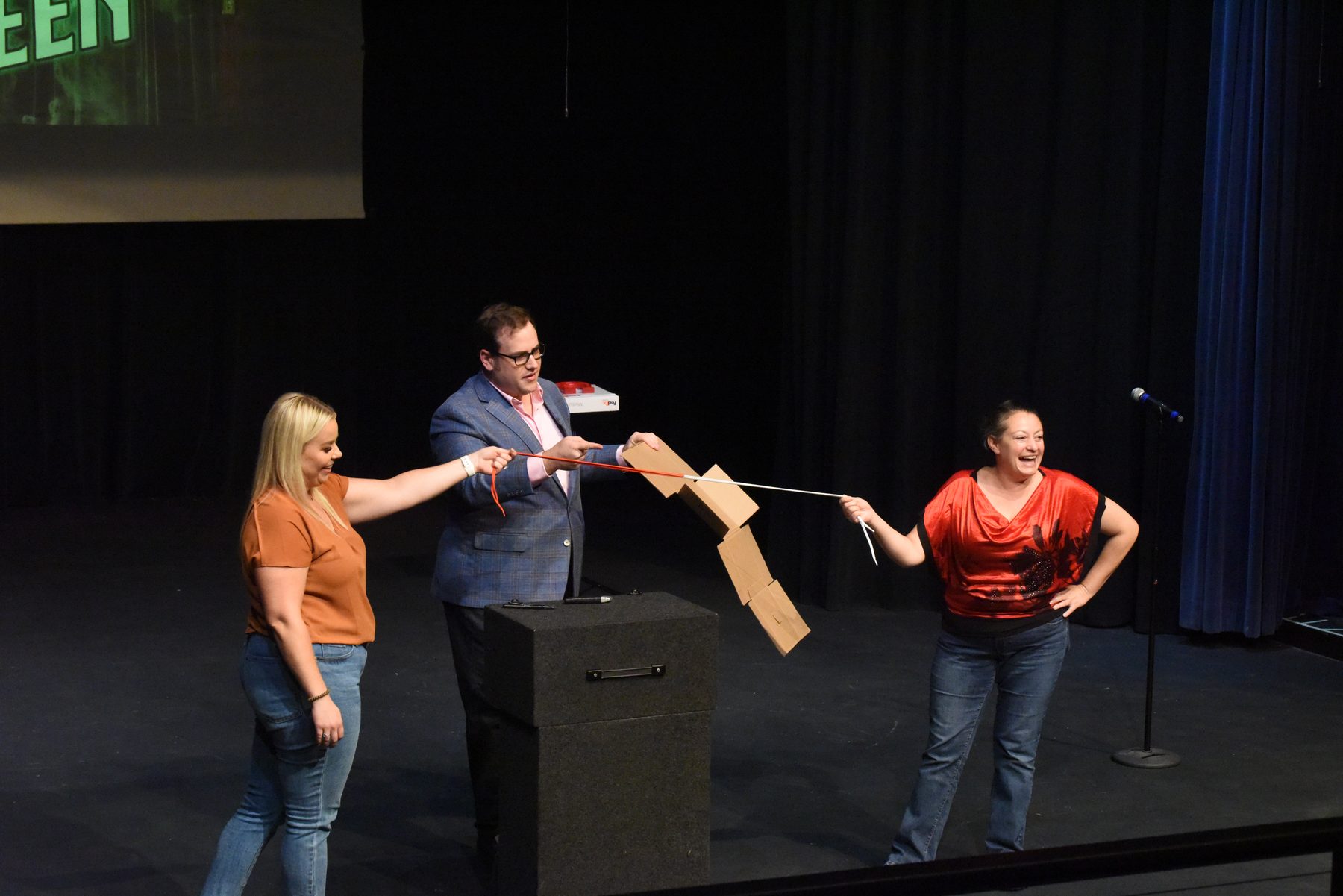 Two volunteers on stage with Scott Green during a show